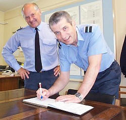 Air Commodore Jon Chitty signs the North Region Visitors Book as Group Captain Bill Gambold looks on