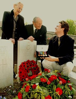 Pictured at the grave of Flight Lieutenant Bruce Arthur Rogers in Ambleteuse cemetery his widow Deborah Rogers and his brother Neville recount memories with the latest Bruce in the family Mr Bruce Thompson, the Great Nephew of Flight Lieutenant Rogers